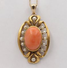 An Art Nouveau era angel skin coral and pearl pendant crafted in 14K gold with a rich bloomed finish. This piece was originally a brooch but now lives on as a wearable pendant. The center coral displays that soft pinkish orange color with some natural white graining and measures 14 mm long by 10 mm wide. Shimmery pearls are set around the coral. A lovely piece! Metal: 14K Yellow Gold (acid tested) Weight: 5 grams Coral: 14 mm long by 10 mm wide Measurement: 1.2 inches long (additional 0.25 inch Formal Coral Jewelry With Cabochon Details, Formal Coral Jewelry With Cabochon, Classic Coral Jewelry As Gift, Classic Coral Jewelry Gift, Vintage Coral Jewelry For Anniversary, Elegant Oval Coral Jewelry, Elegant Coral Oval Jewelry, Coral Vintage Jewelry For Anniversary, Elegant Coral Jewelry For Anniversary