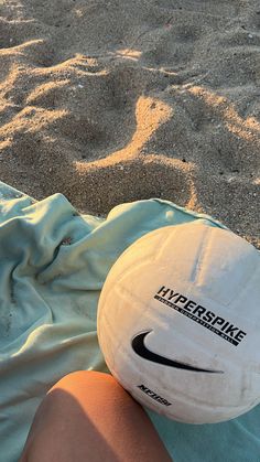 a white frisbee sitting on top of a beach next to someone's legs