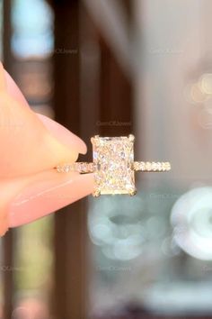 someone is holding an engagement ring with a princess cut diamond in it's center