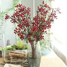 a vase filled with red berries sitting on top of a table