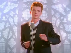 a man wearing a suit and tie standing in front of a wall with geometric designs