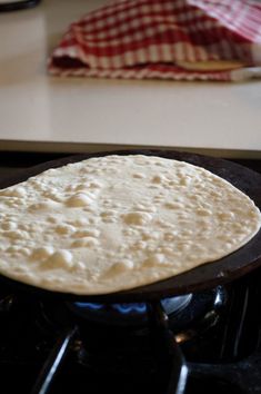 an uncooked tortilla sitting on top of a black stove burner