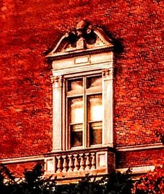 a red brick building with an open window and balcony railing on the top right side