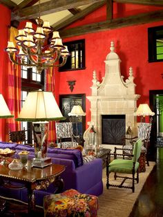 a living room filled with lots of furniture next to a fire place in a red wall