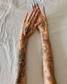 two hands with tattoos on them laying on a bed