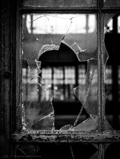 a broken glass window with the reflection of a building in it