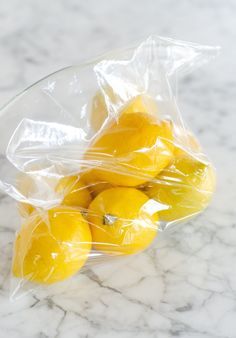 a plastic bag filled with lemons on top of a marble counter