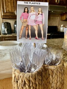 two women in pink shirts are standing next to a basket with plastic wrappers on it