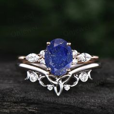 an oval shaped blue diamond surrounded by white diamonds on top of a wooden table with green leaves