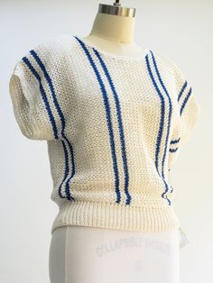 Vintage Christian Dior knit sweater. Gorgeous cream color with navy blue stripes and removable shoulder pads. Size: Small Length: 22 inches Pit to pit: 18 inches Sleeves: 3 inch cap sleeve Waist, taken flat: 13 inches, with extra stretch Pockets: None Lining: None Fasteners: Single back button, intact and functioning Color: White and navy Fabric: 100% cotton Care: Hand wash in cold water, lay flat to dry Condition: NOSWT Striped Textured Knit Cotton Top, Striped Knitted Cotton Top, Knit Sweater With Contrast Stripes Crew Neck, Knit Crew Neck Sweater With Contrast Stripes, Striped Knitted Crew Neck Tops, Striped Cotton Summer Sweater, Striped Textured Knit Top, Striped Textured Knit Cotton Sweater, White Knit Sweater With Contrast Stripes