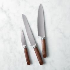 two knives are sitting next to each other on a marble counter top with wood handles