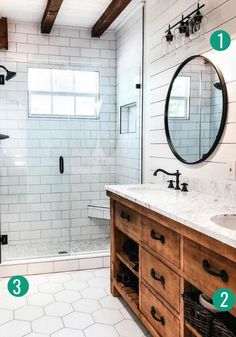 a bathroom with two sinks, mirrors and a walk in shower stall that has white tile on the walls