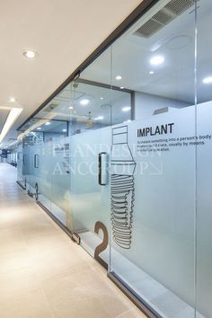 an empty hospital hallway with glass walls and signs on the wall that say implants