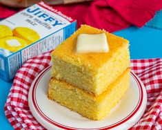 two pieces of cake sitting on top of a plate next to a carton of jelly