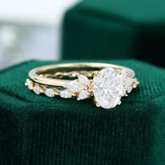 a close up of a ring on top of a green velvet cushioned box with a white diamond in the center