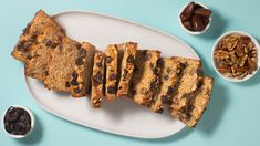 a white plate topped with slices of cake next to nuts and raisins