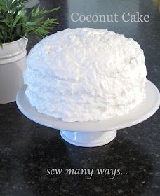 a white cake sitting on top of a table next to a potted plant and a sign