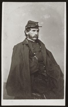 an old black and white photo of a man with a hat on his head wearing a cape