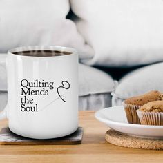 a cup of coffee sitting on top of a table next to a plate with muffins