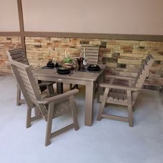 an outdoor table and chairs set up in front of a brick wall with food on it