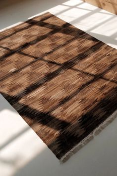 a brown and black rug sitting on top of a white floor next to a window