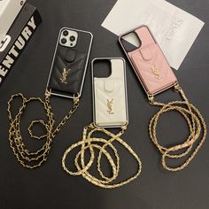 three cell phones are laying next to each other on a table with gold chains around them