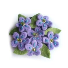 small purple flowers with green leaves on white background, ready to be made into brooches