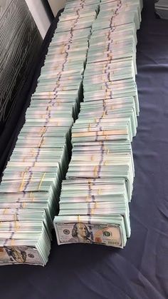 stacks of twenty dollar bills sitting on top of a blue cloth covered floor next to a wall