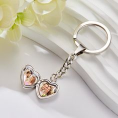 a keychain with two pictures on it and a flower in the back ground