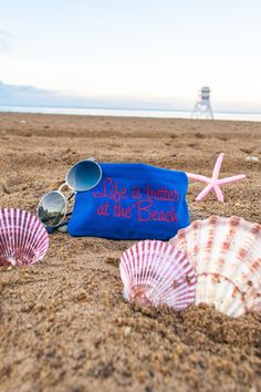 three seashells and sunglasses on the beach with a sign that says life is better at the beach