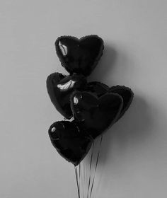 three black heart shaped balloons hanging from the wall