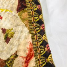 a close up of a pillow on a white surface with flowers and leaves in the background