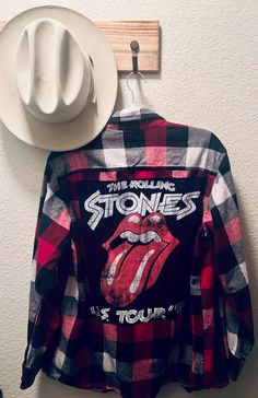 the rolling stones flannel shirt hanging on a wall with a cowboy hat next to it