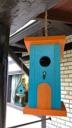 a blue birdhouse hanging from the side of a building