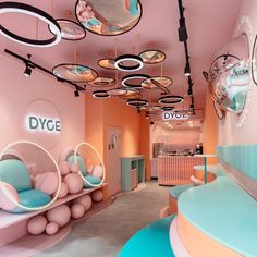 the interior of a pink and blue store with circular mirrors hanging from the ceiling