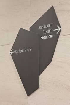 two signs pointing in opposite directions on the wall next to each other that say restaurant elevator, car park elevator, and restaurant elevators