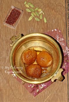 some food is sitting in a gold bowl on a wooden table next to other items