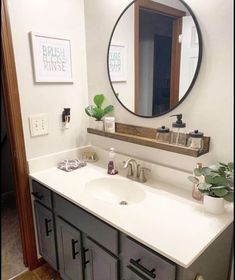 a bathroom sink with a mirror above it and a plant on the counter in front of it