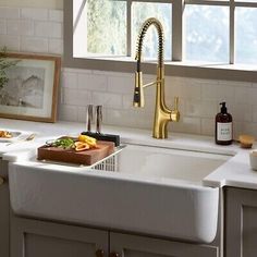 a kitchen sink sitting under a window next to a cutting board and utensils