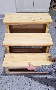 a man kneeling down next to three wooden shelves