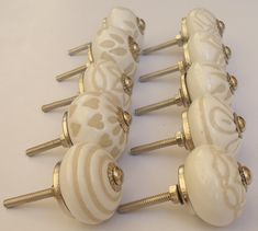 four white and gold knobs with hearts on them are lined up against a white background