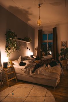 a bed room with a neatly made bed next to a window and potted plants