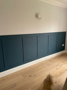 an empty room with wood floors and blue paneling on the wall, in front of a window