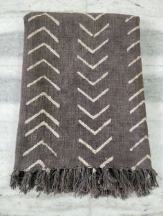 a brown and white rug with fringes on it's edges, sitting on a marble floor