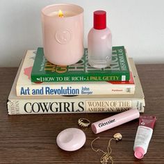 a candle, lipstick, and other items are sitting on top of books