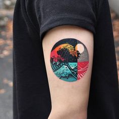 a person with a tattoo on their arm that has an image of the ocean and mountains