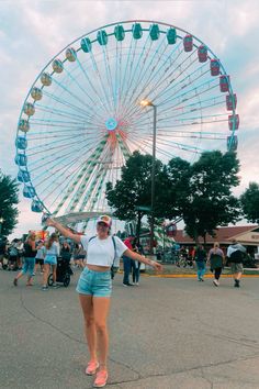 a woman standing in front of a large ferris wheel