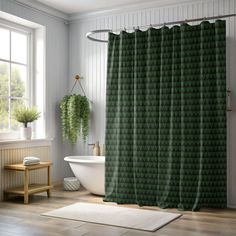 a bathroom with a green shower curtain next to a white bath tub and wooden floor