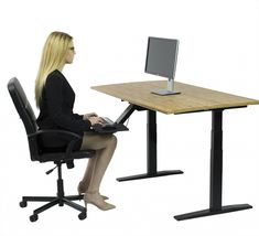 a woman sitting at a desk with a computer on her lap top and legs crossed