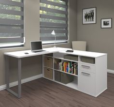 a computer desk with a laptop on top of it next to a book shelf and window